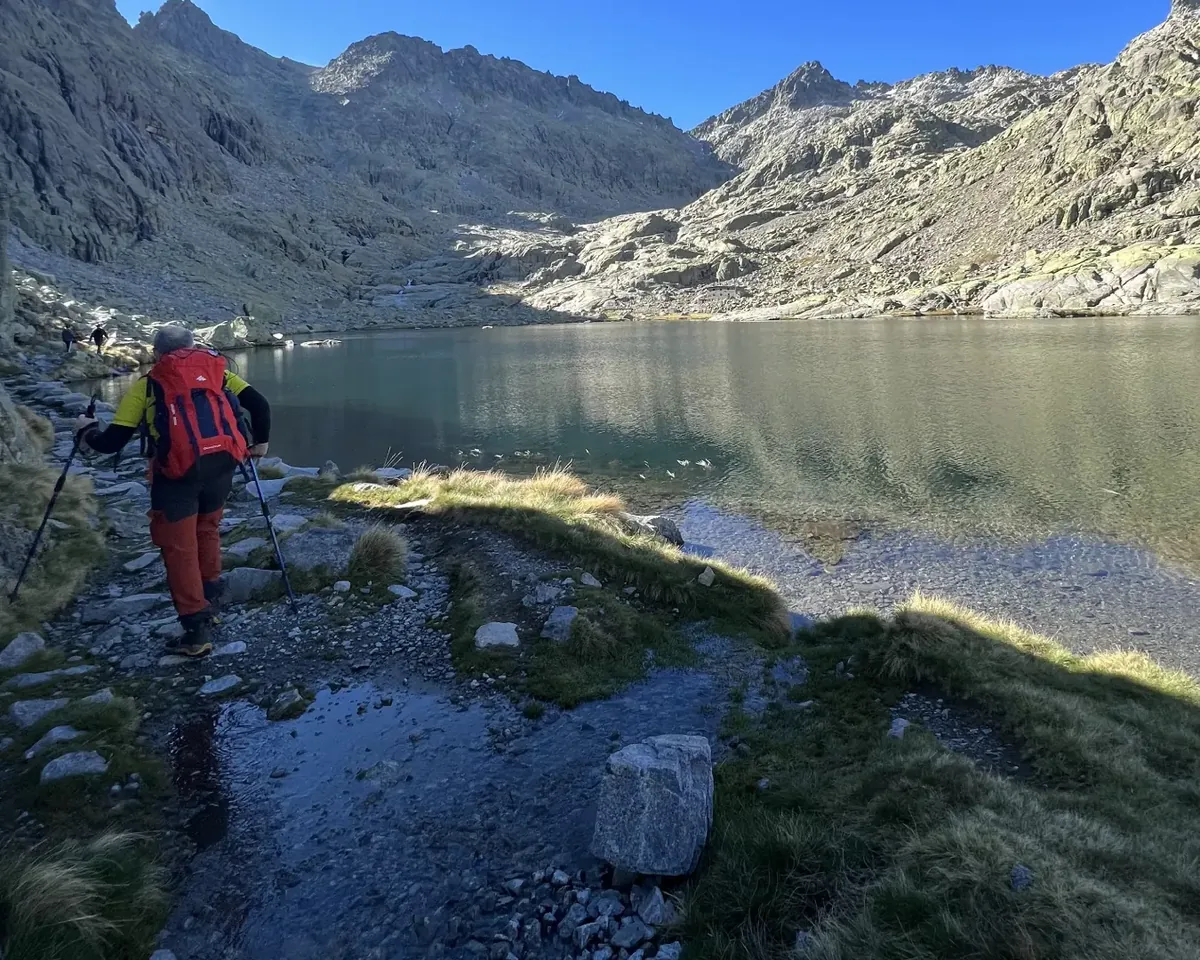 Senderista con mochila junto a una laguna de montaña